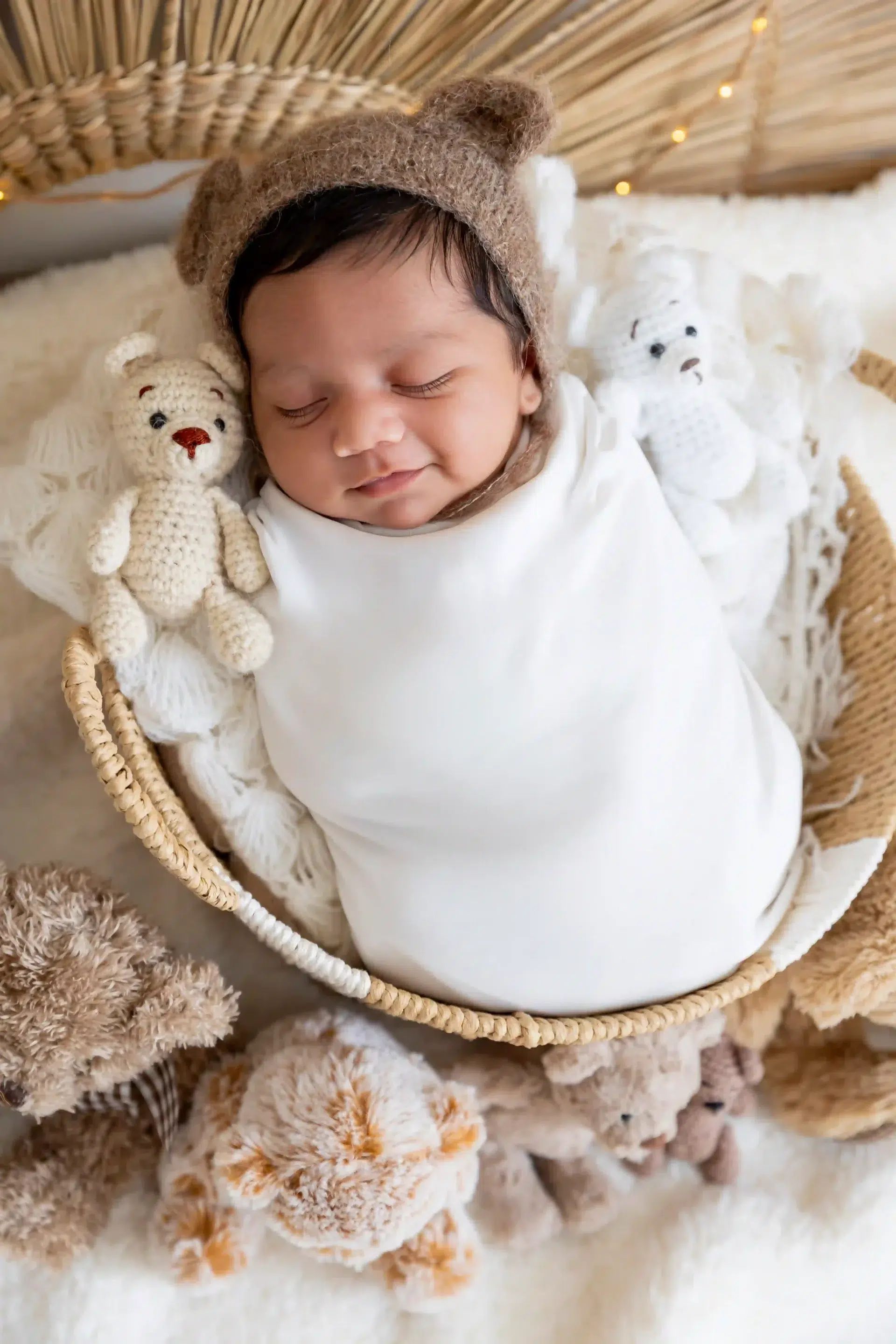 photo de naissance, un bébé emmailloté avec un bonnet en ourson et souriant