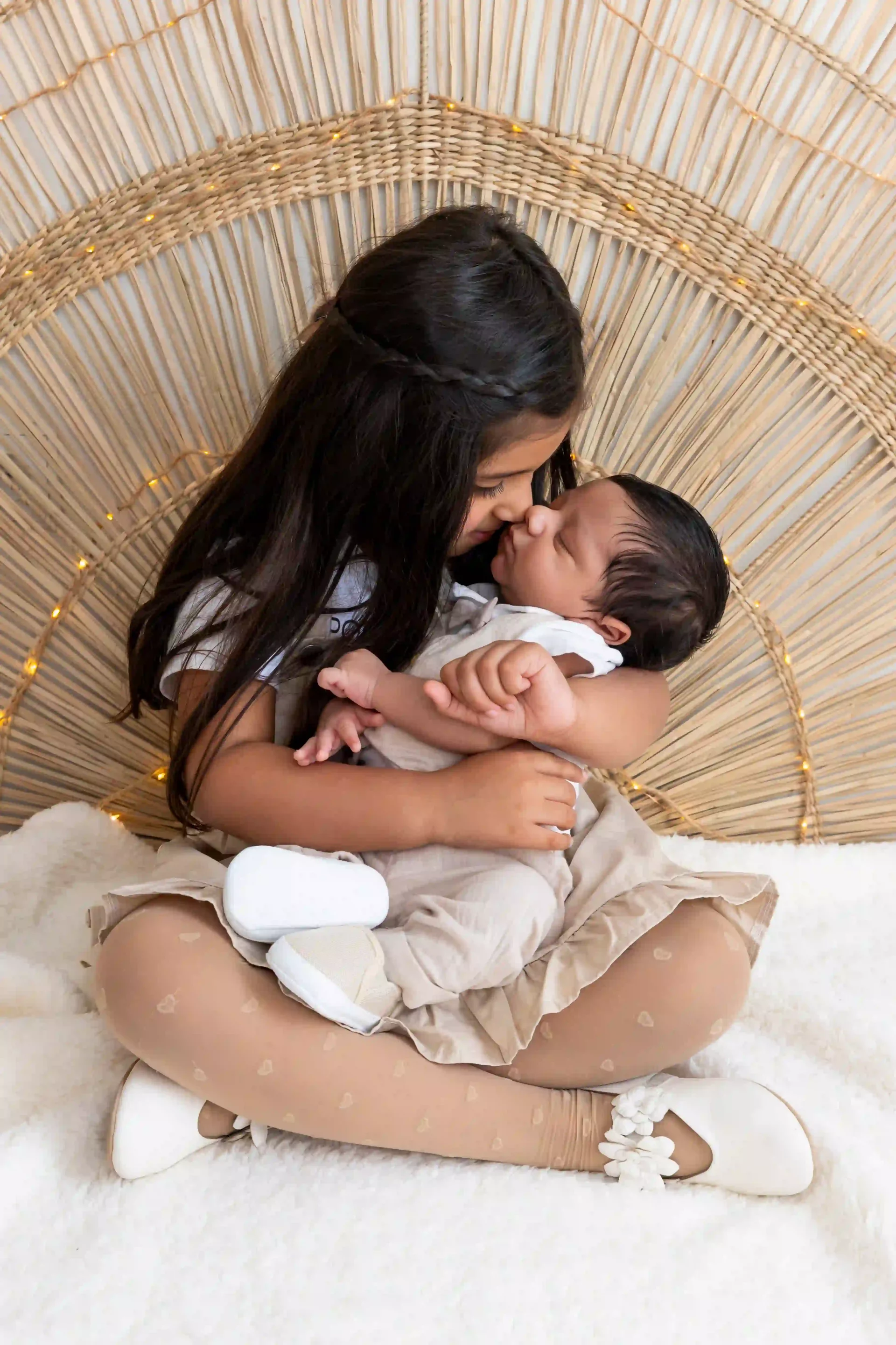 photo de naissance, grande sœur qui fait un bisou esquimau à son petit frère