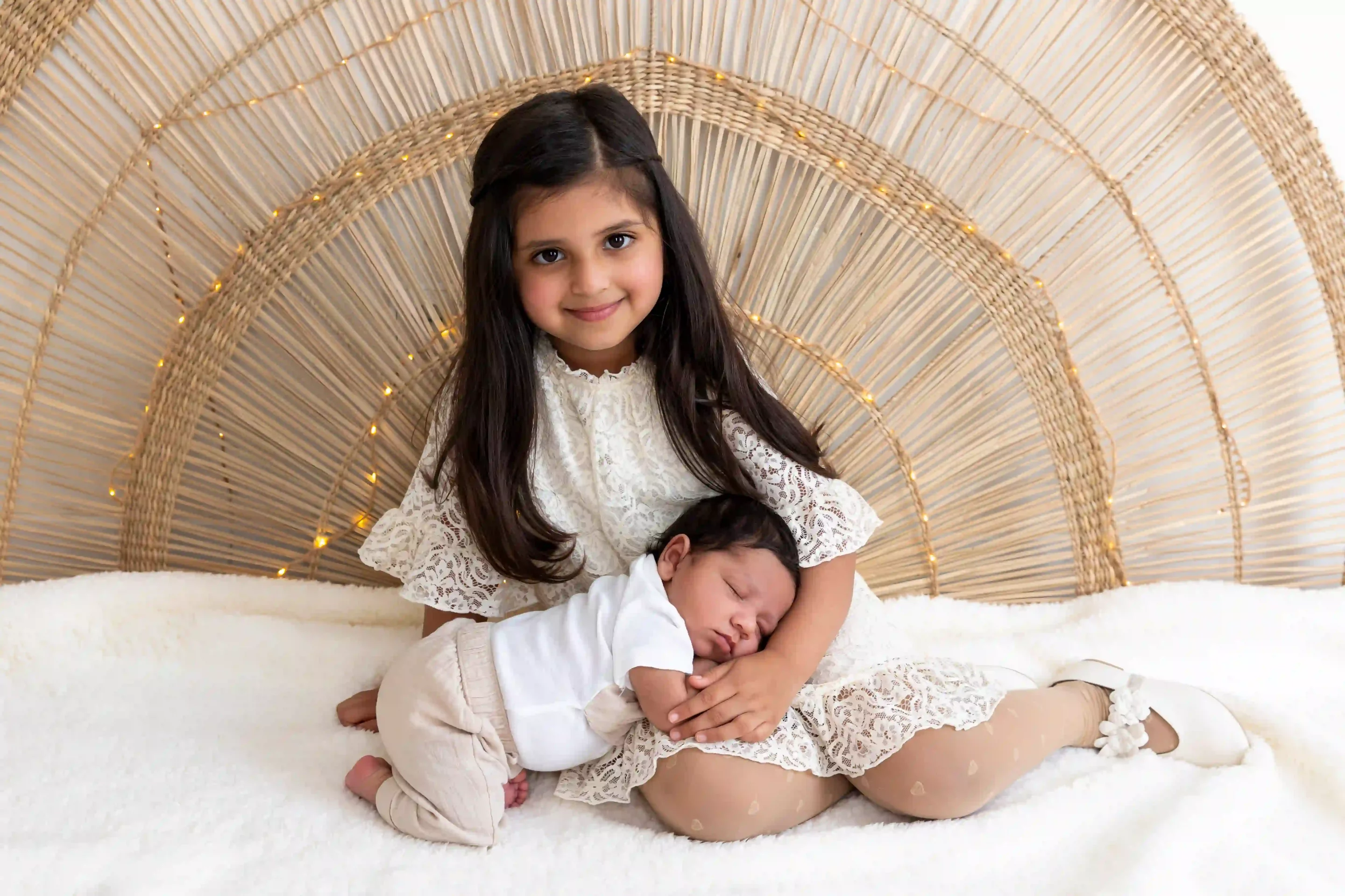 photo de naissance, une grande sœur tenant son petit frère endormi sur les jambes