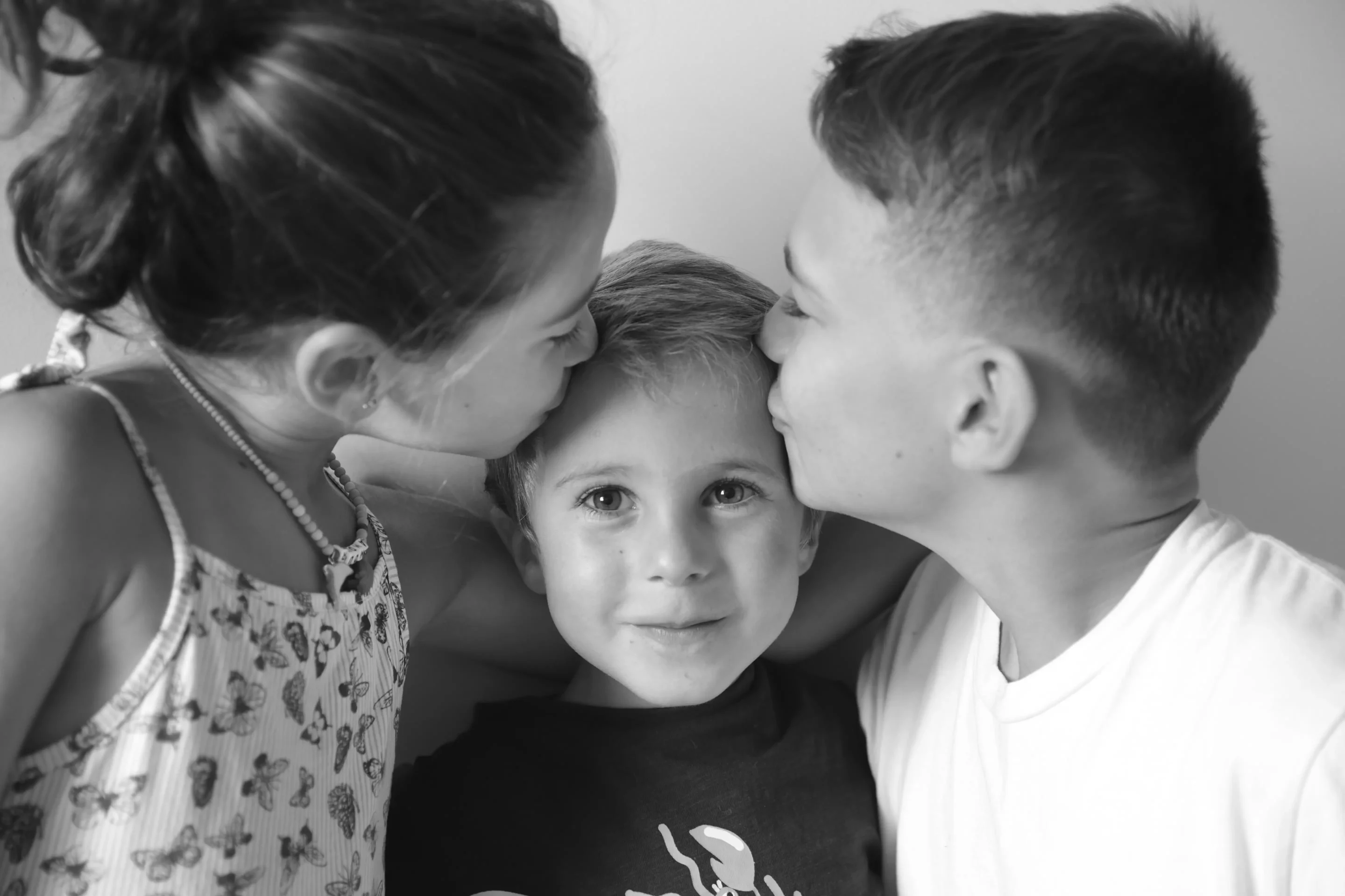 photo frères sœur, les deux grands embrassent le petit sur les tempes