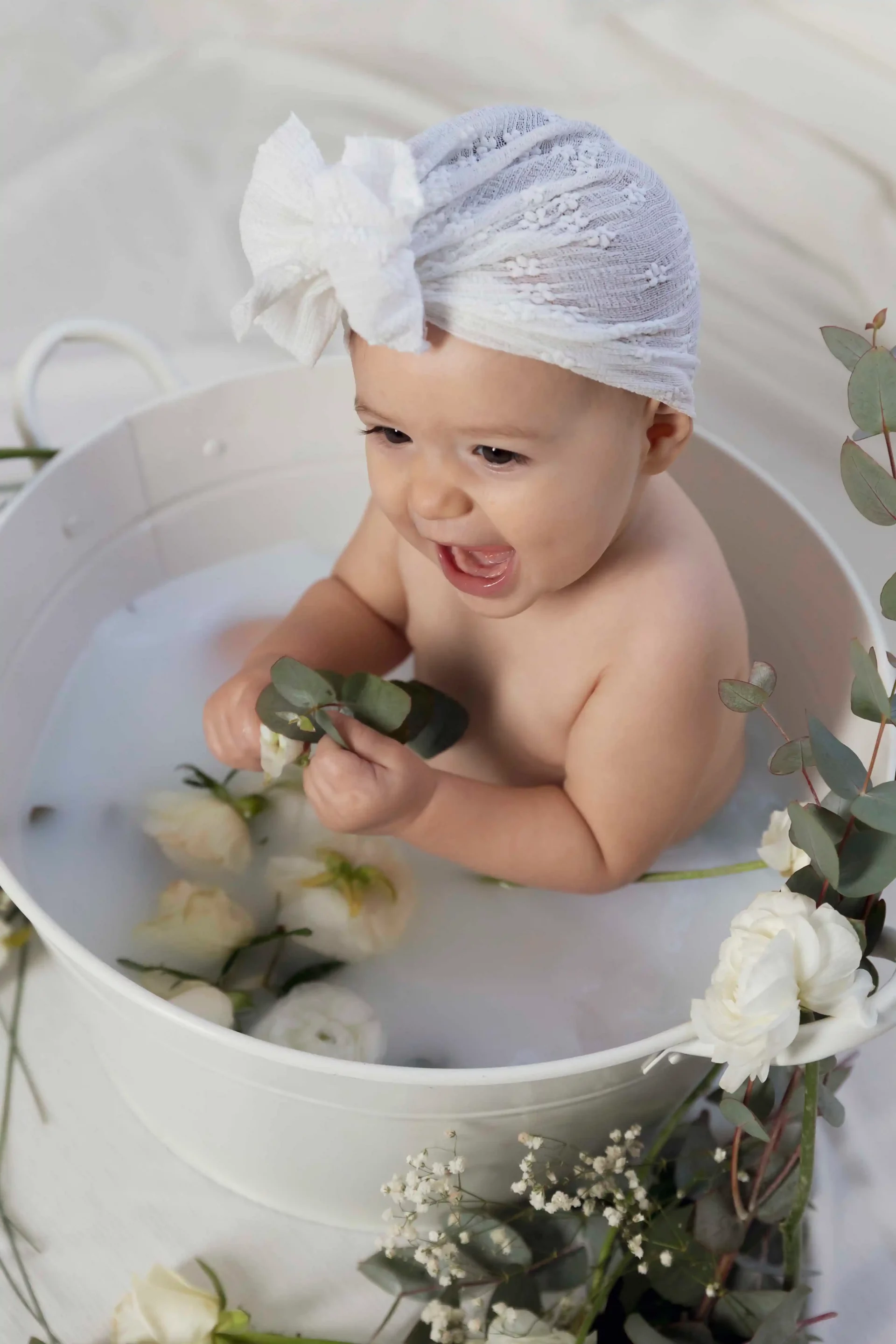 photo bain de lait, bébé entourée de fleurs blanches