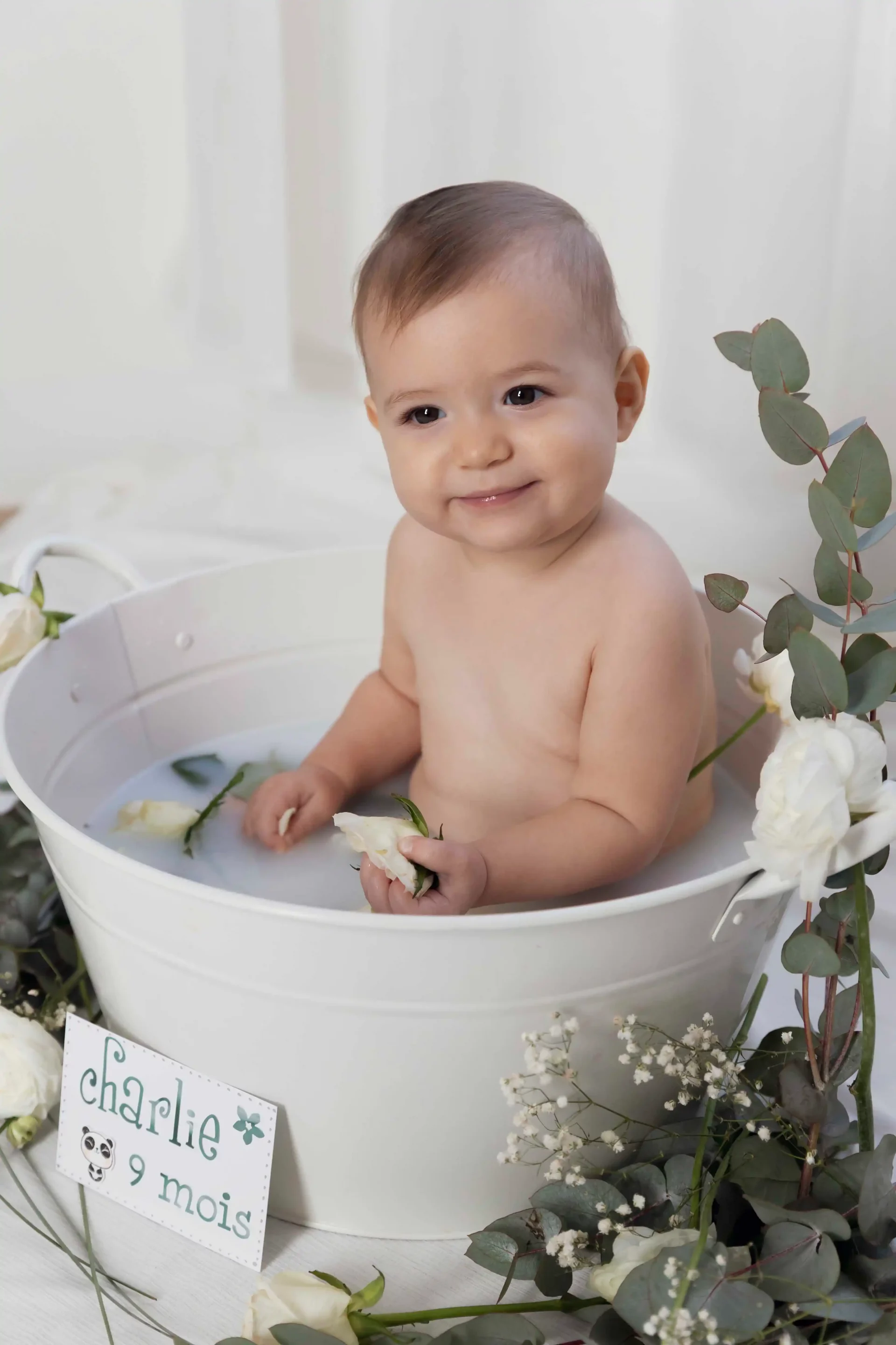 photo bain de lait, bébé entourée de fleurs blanches