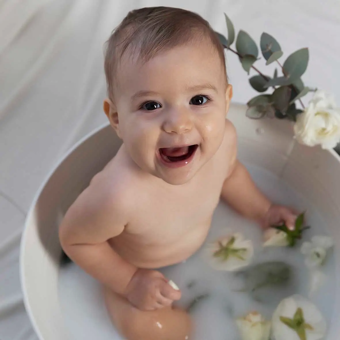 photo de bain de lait, bébé entouré de fleurs blanches