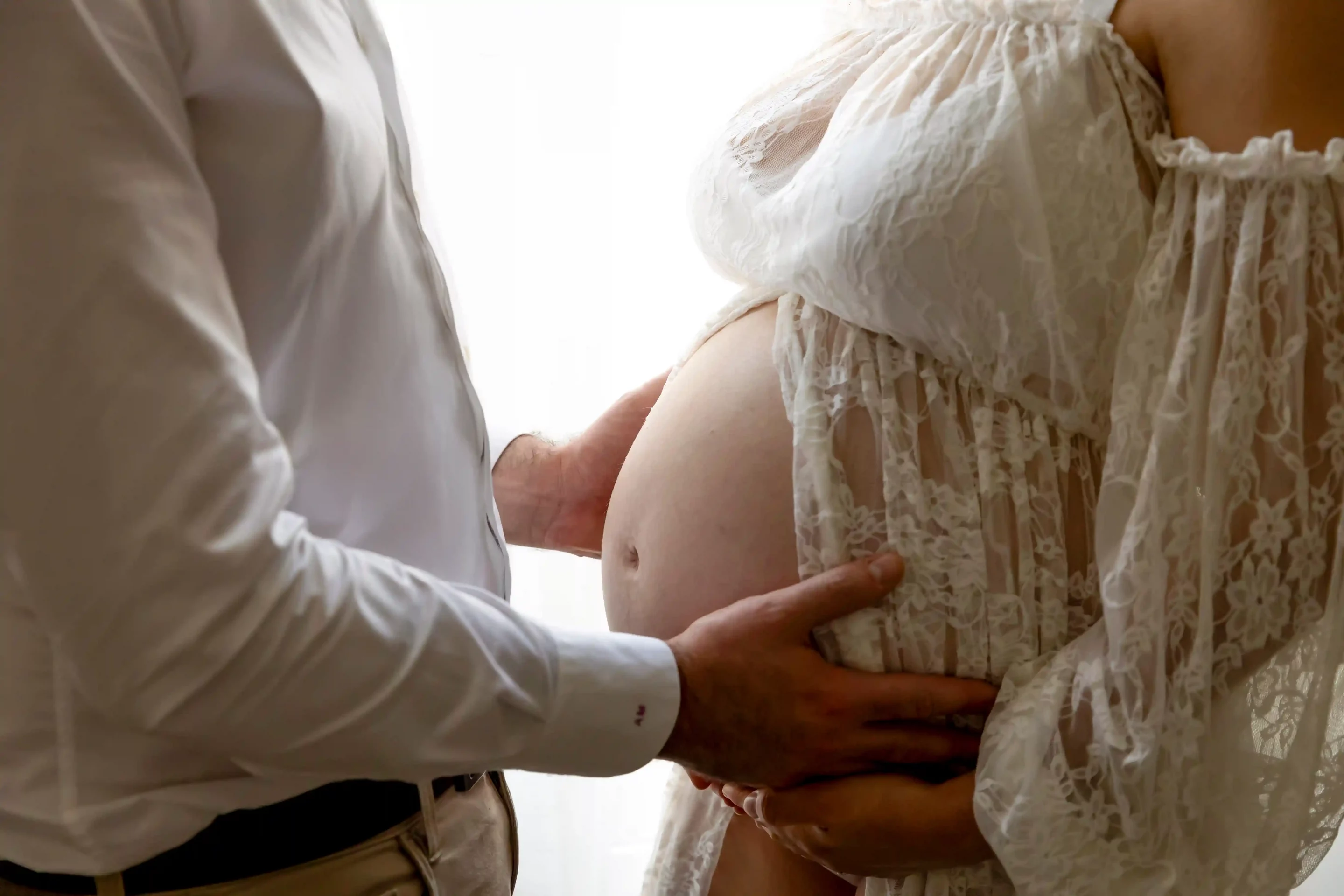 photo de grossesse, gros plan sur les mains du papa posées sur le ventre de la maman