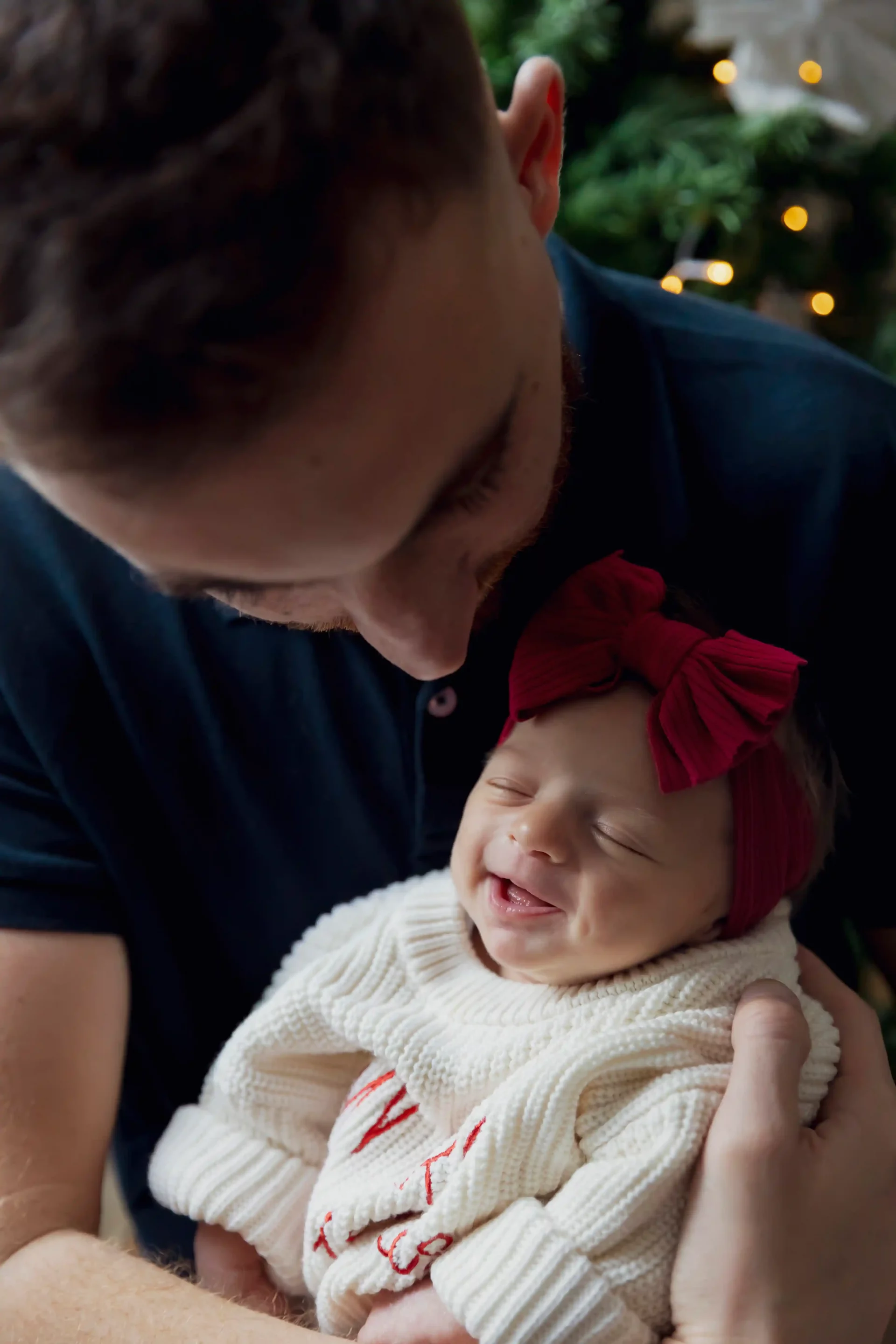 photo de naissance, un bébé sourie aux anges dans les bras de son papa