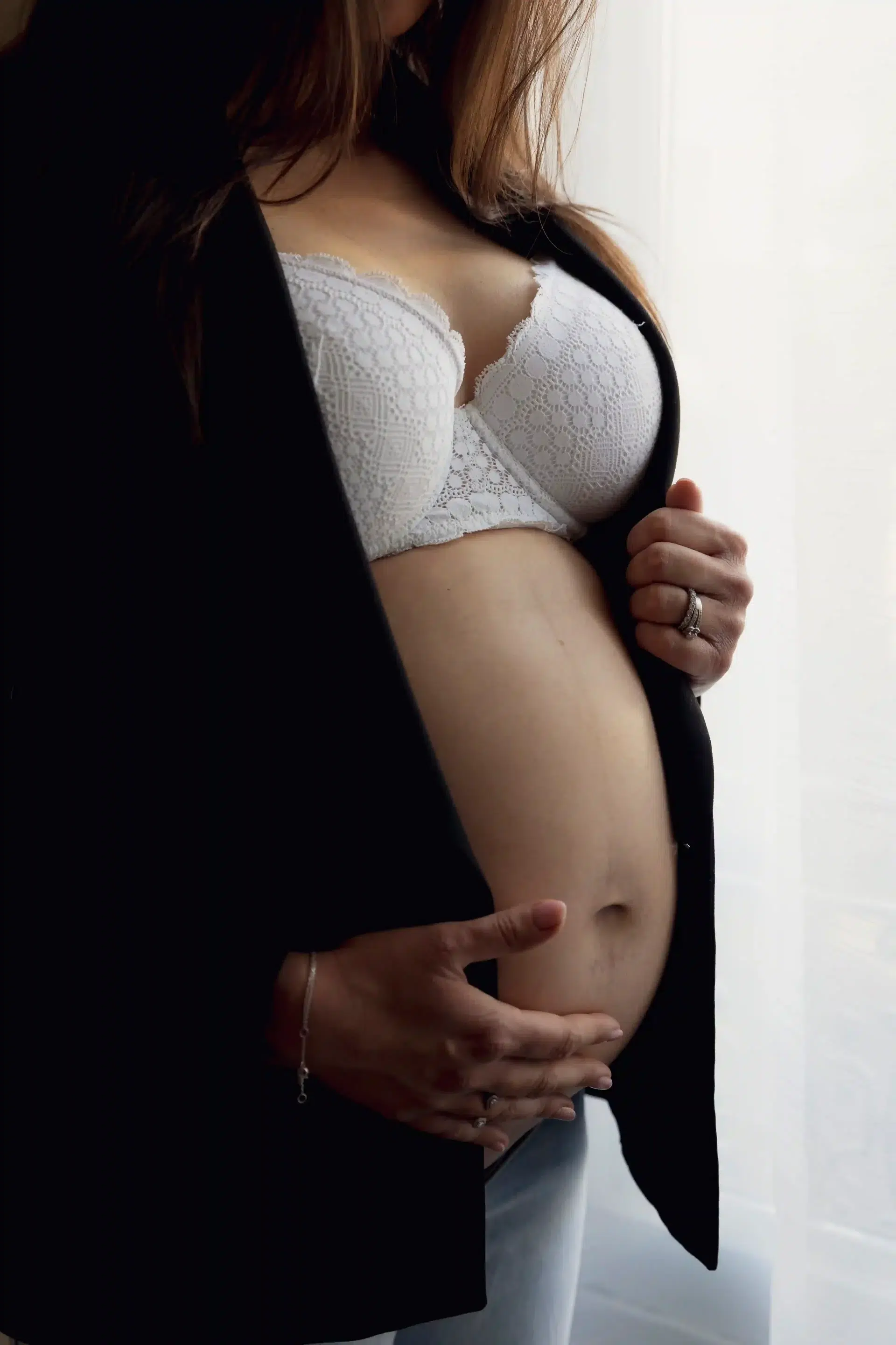 photo de grossesse, maman habillée d'une veste noire, montrant le ventre