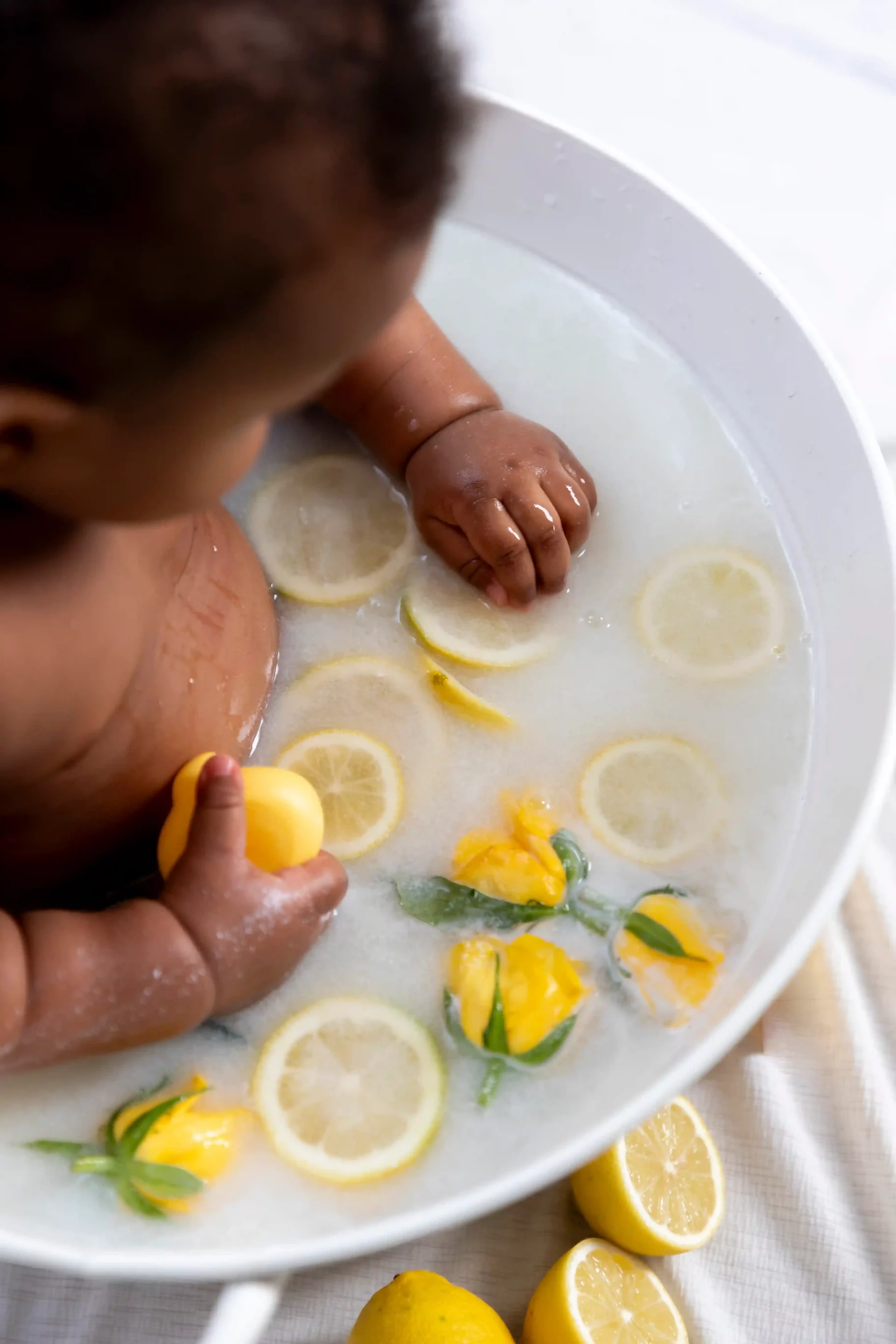 photo bain de lait, bébé dans entouré de citrons et de roses jaunes