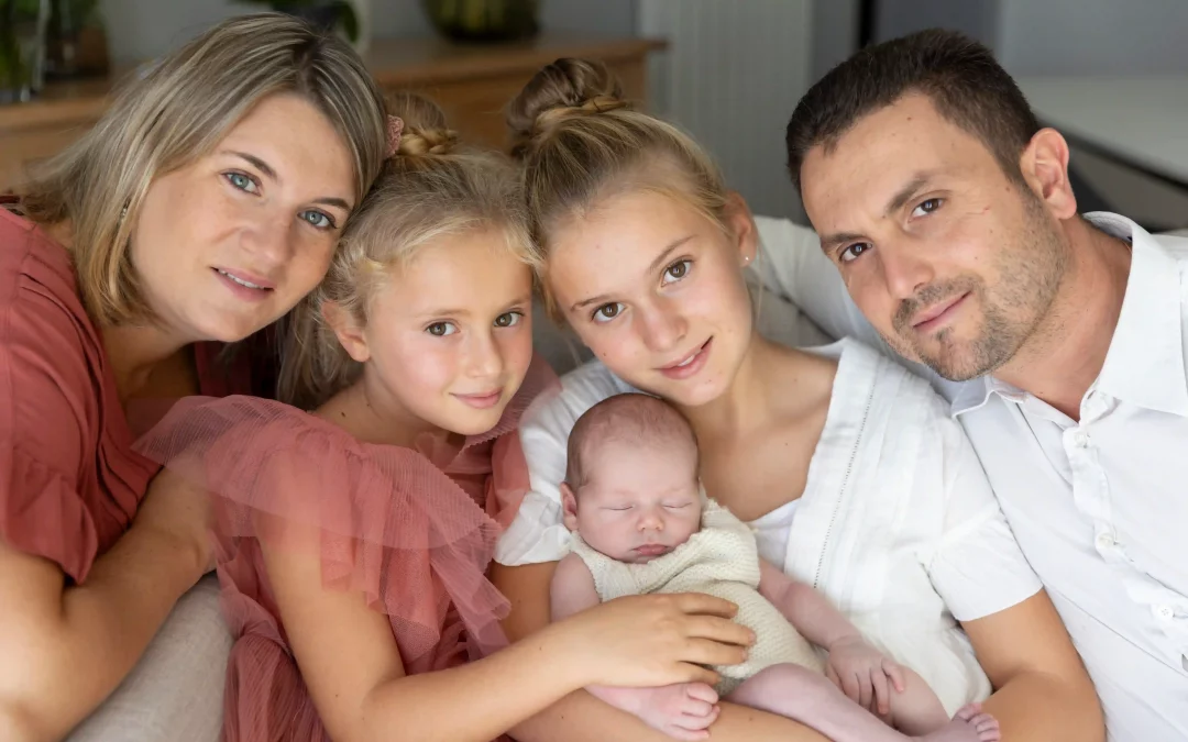 photo de famille, parents et sœurs encadrant le bébé