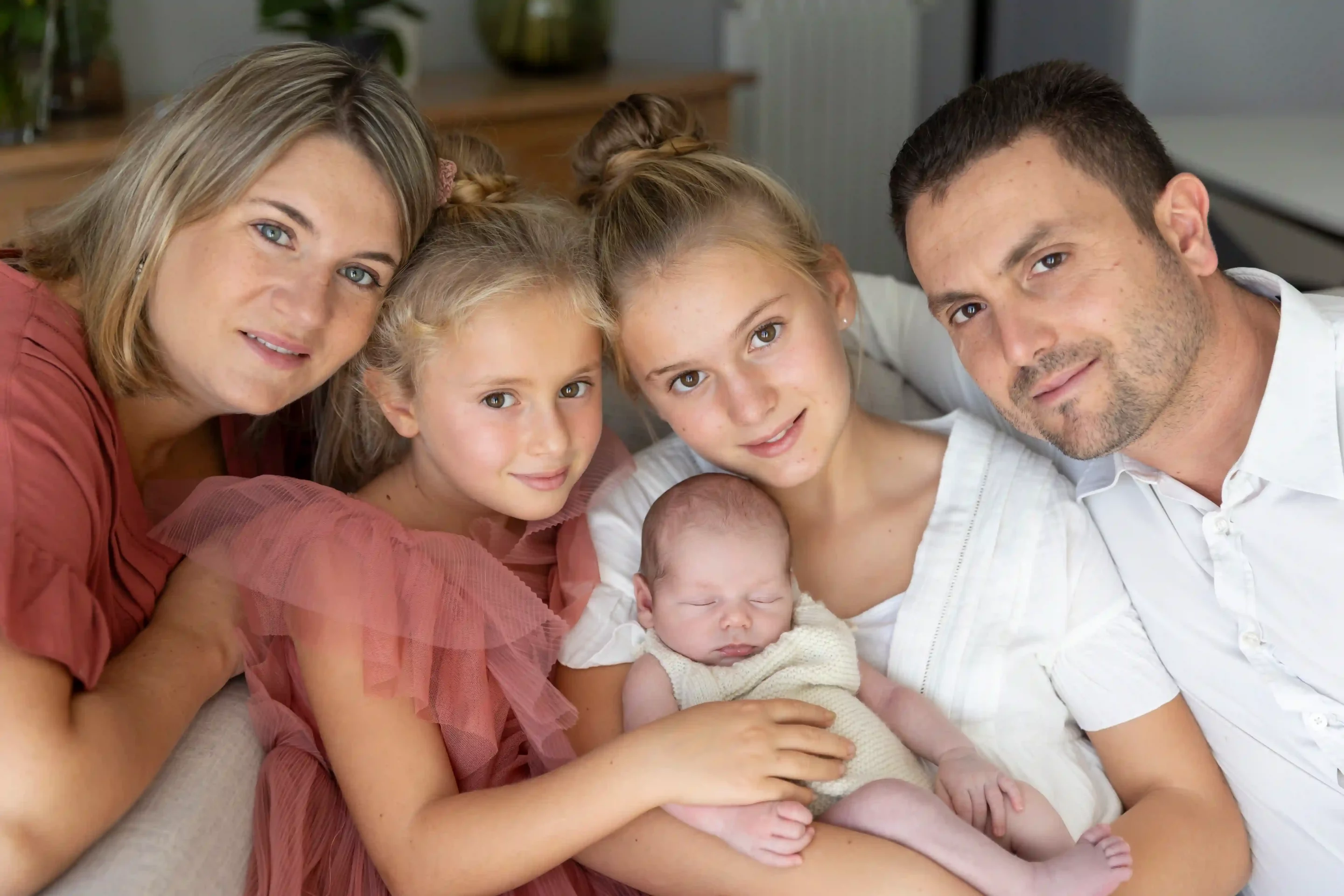 photo de famille, parents et sœurs encadrant le bébé