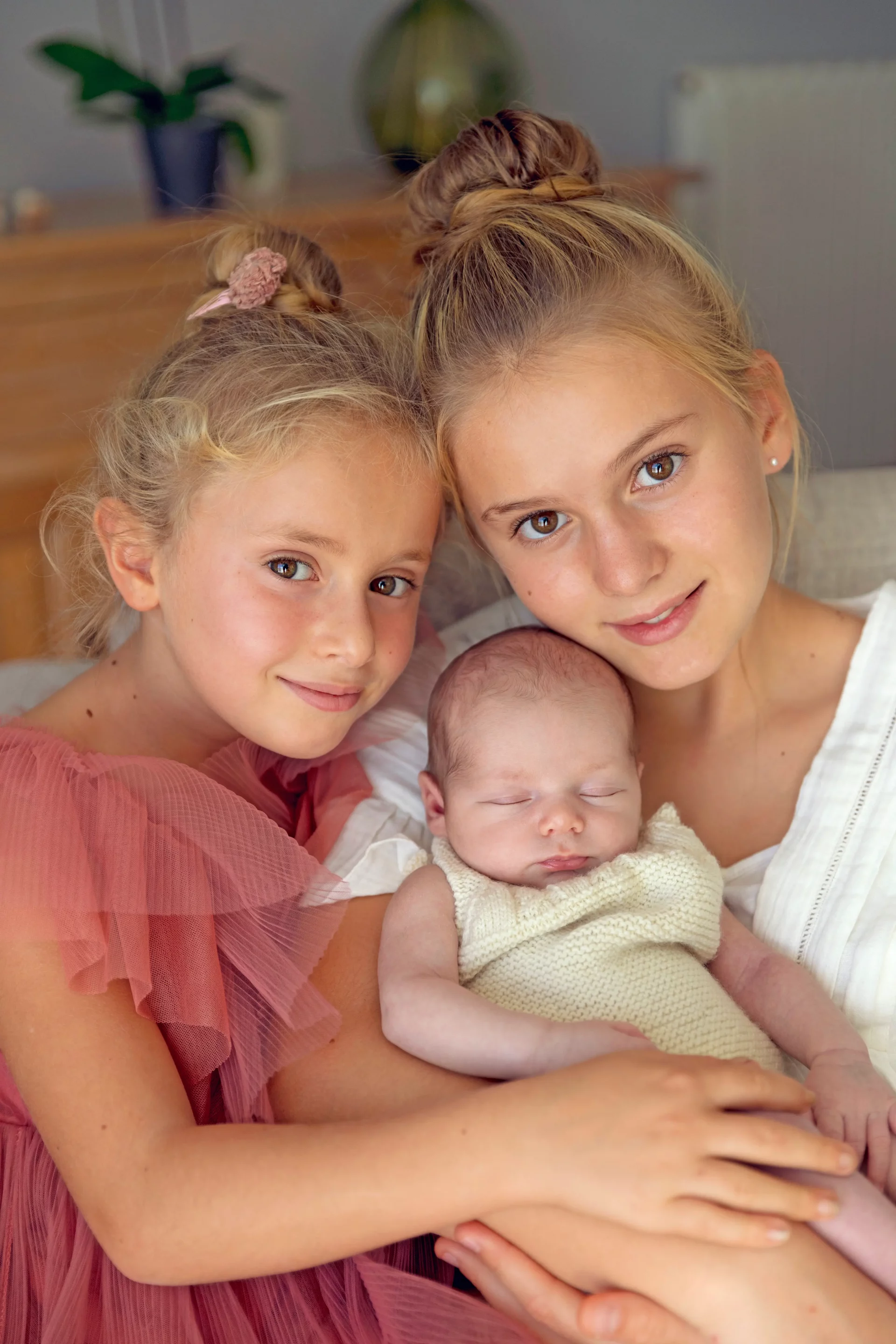 photo de famille, deux sœurs qui portent leur petit frère