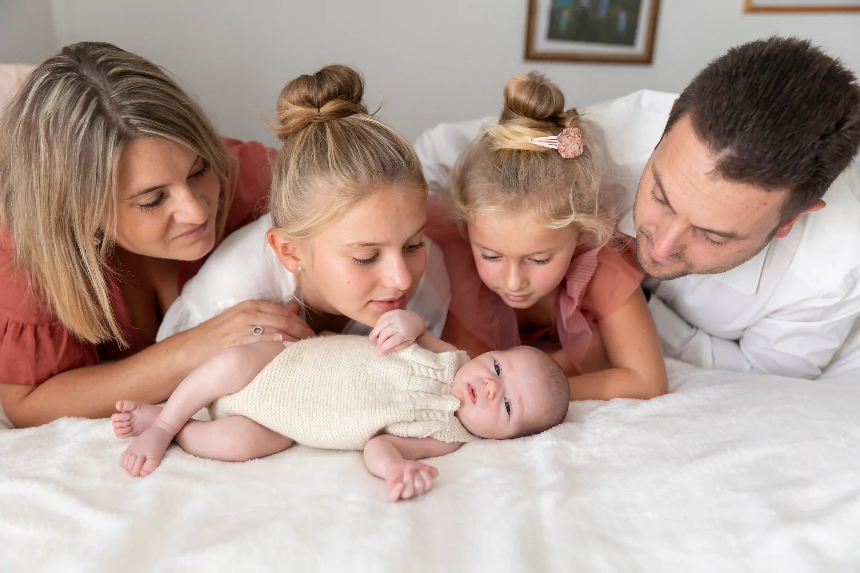 photo de famille, parents et sœurs regardant le bébé