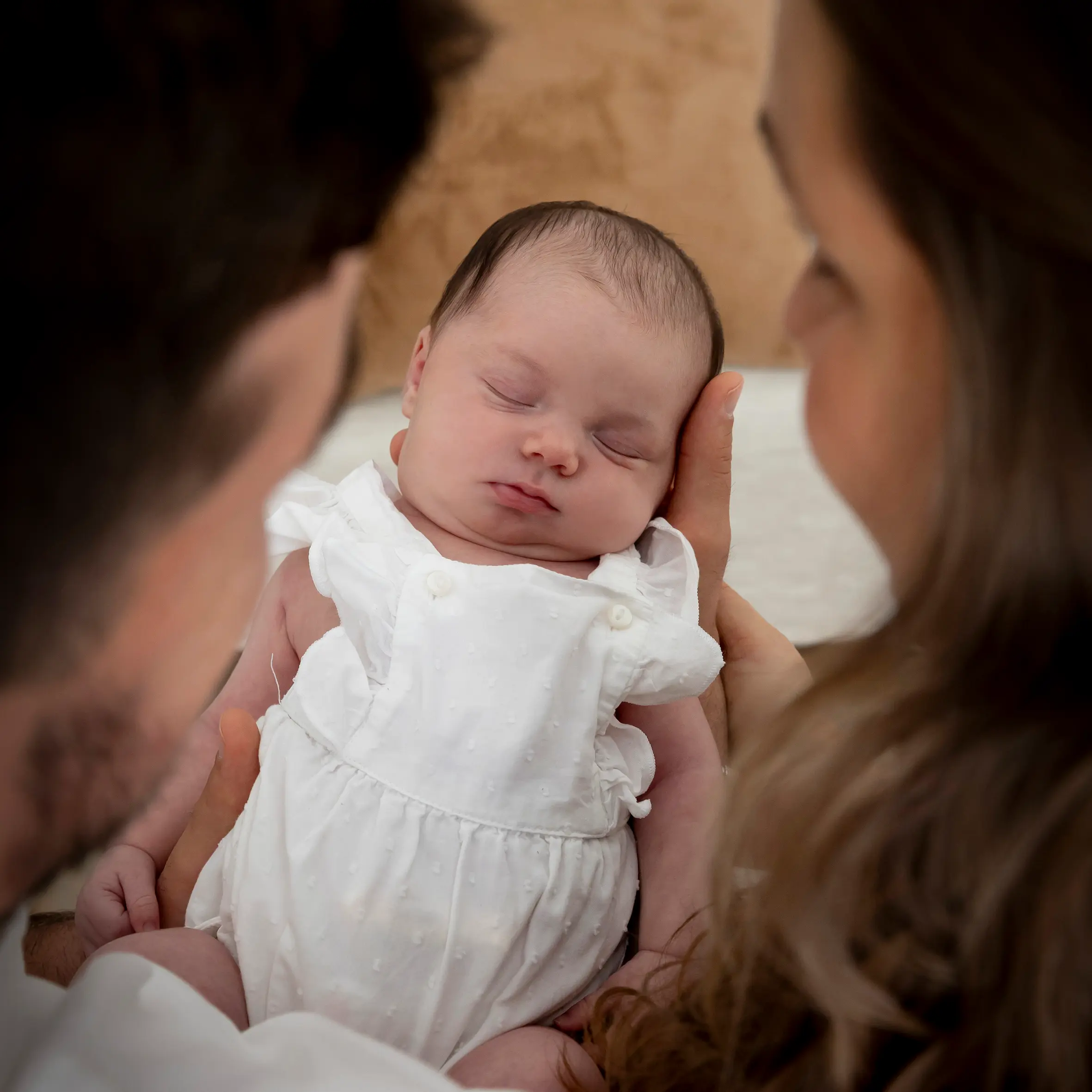 photo de naissance, deux parents se regardant, tenant leur bébé au milieu d'eux