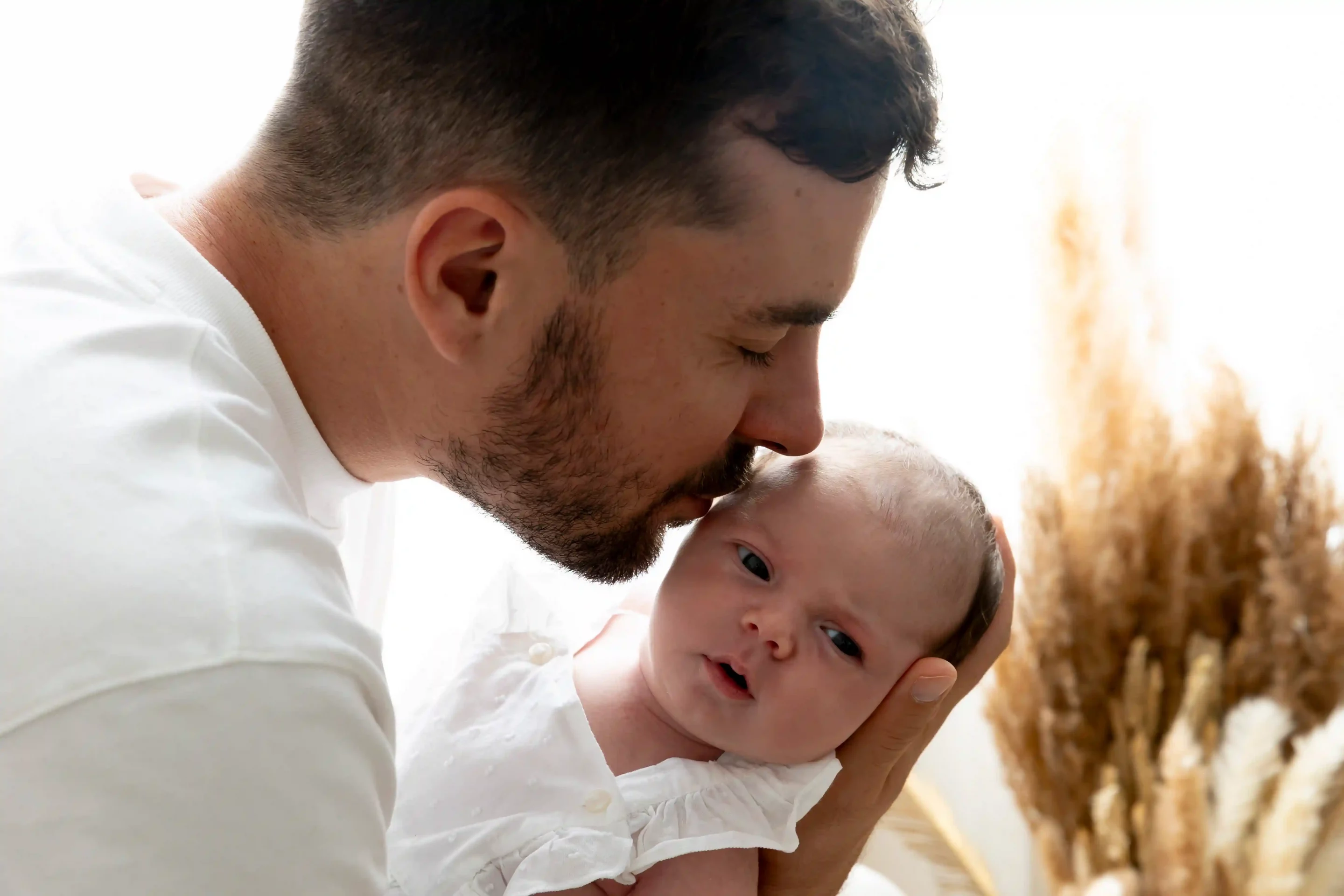 photo de bébé, papa embrassant sa fille dans un décor bohème