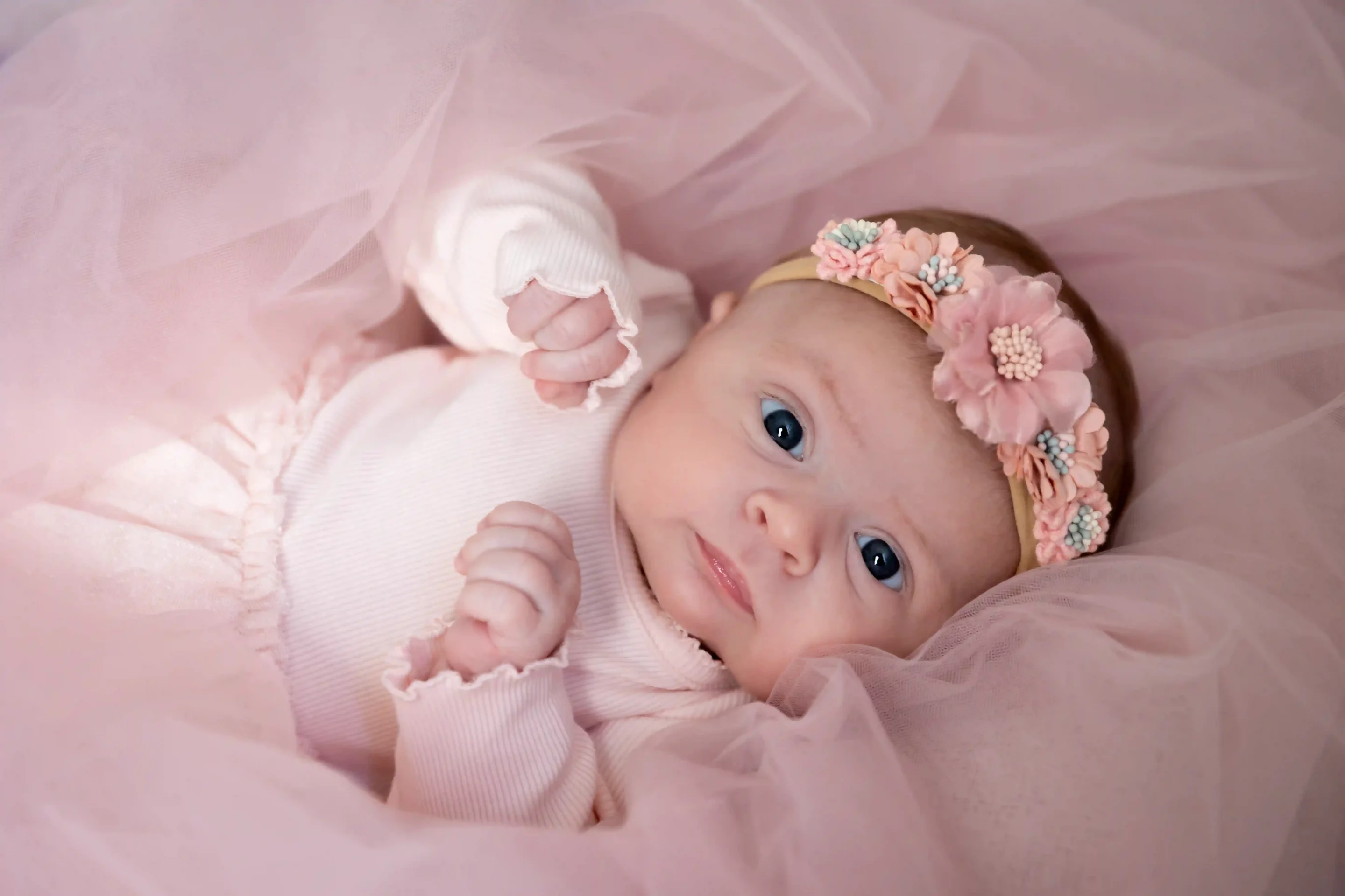 photo de nouveau né, bébé éveillée dans un tulle rose