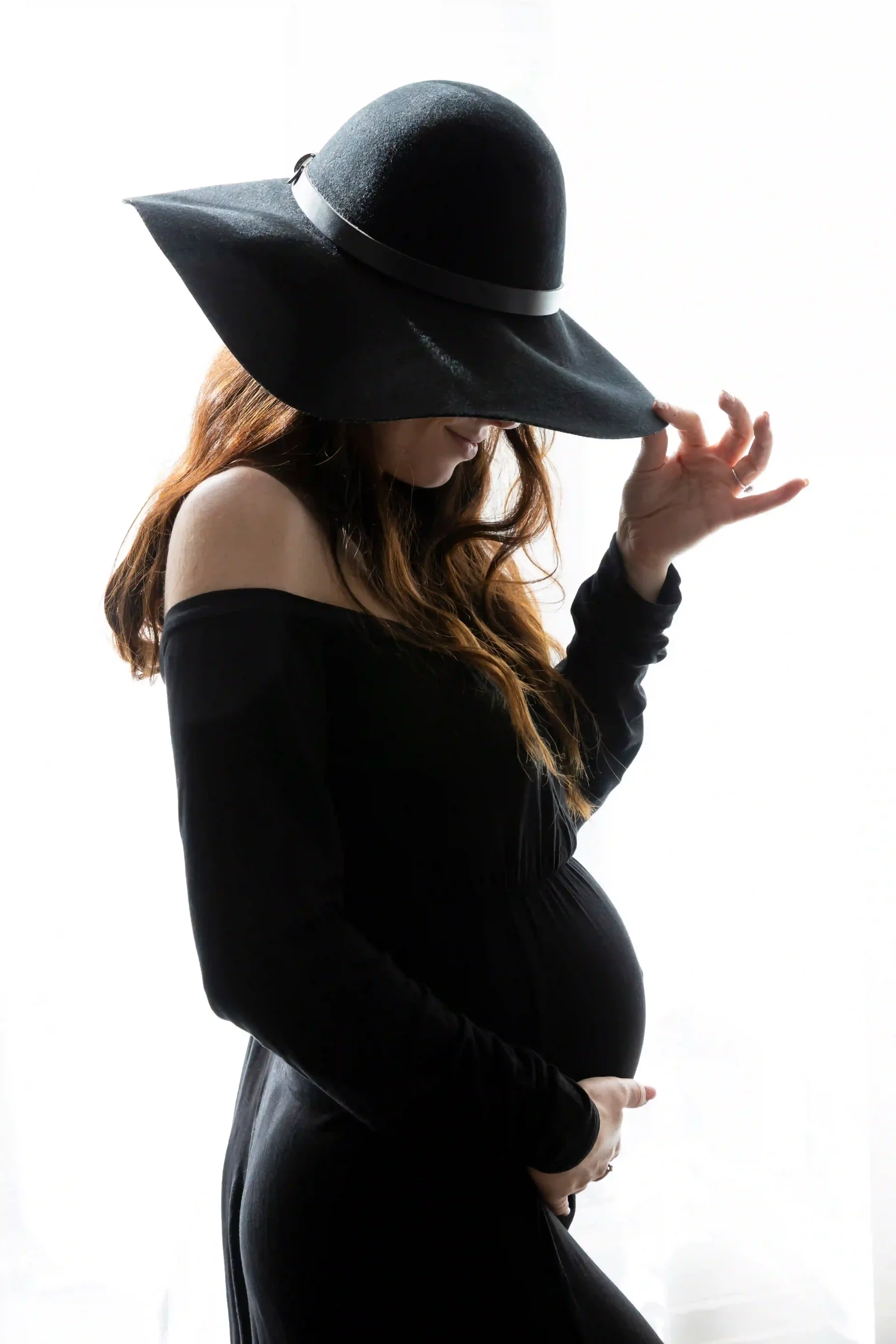 photo de grossesse, maman habillée en robe et chapeau noirs