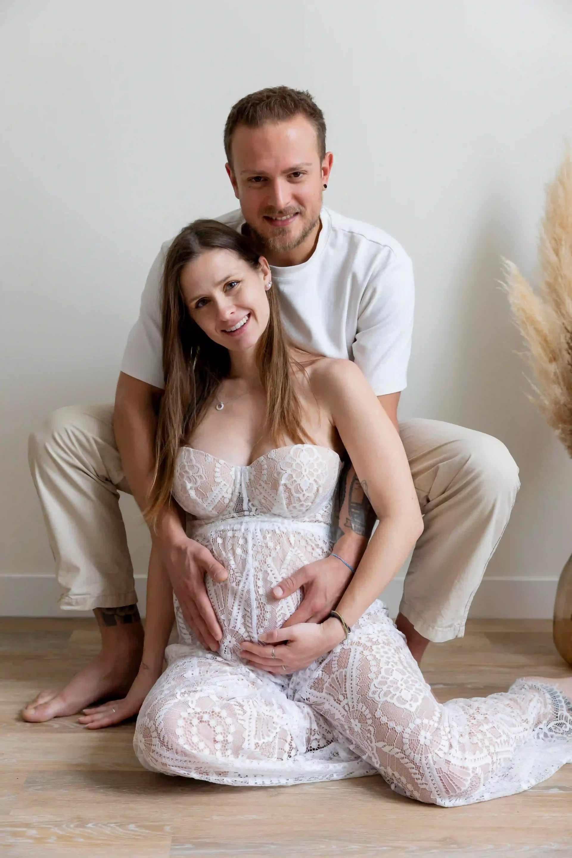 photo de grossesse, couple assis dans un décors bohème