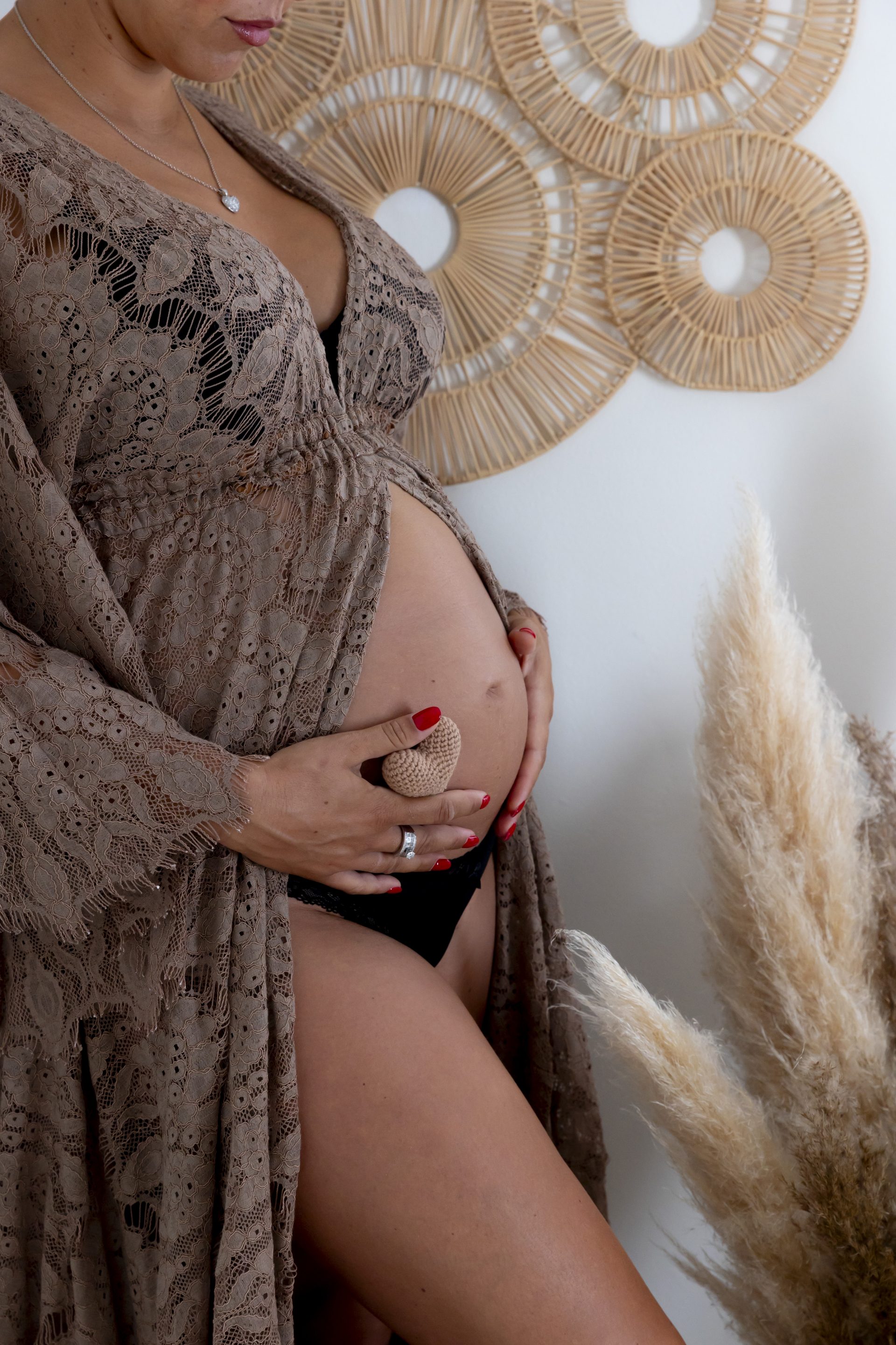photo de grossesse, gros plan sur le ventre de la maman, vêtue d'une robe en dentelle marron
