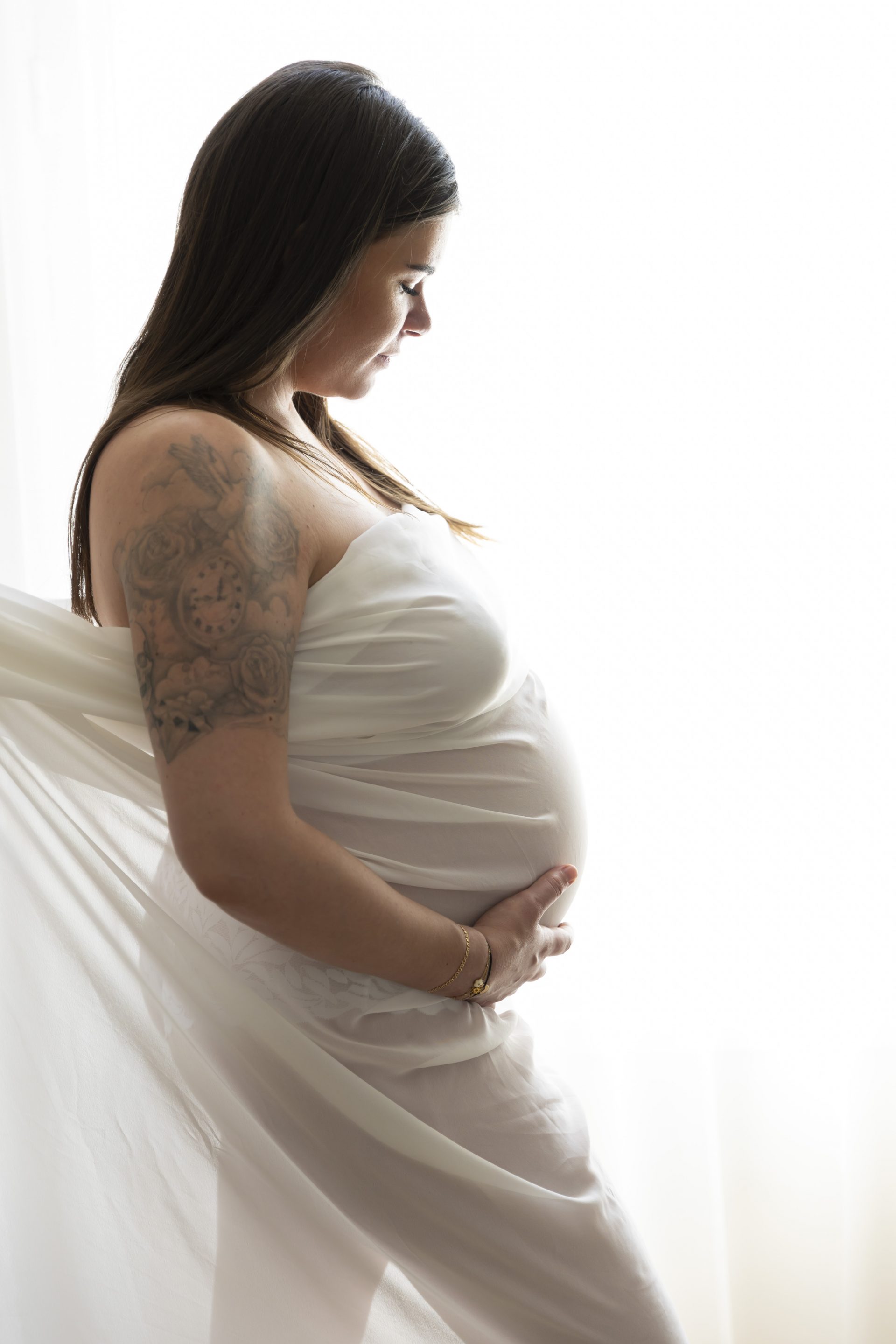 photo de grossesse, future maman habillée d'un voile blanc