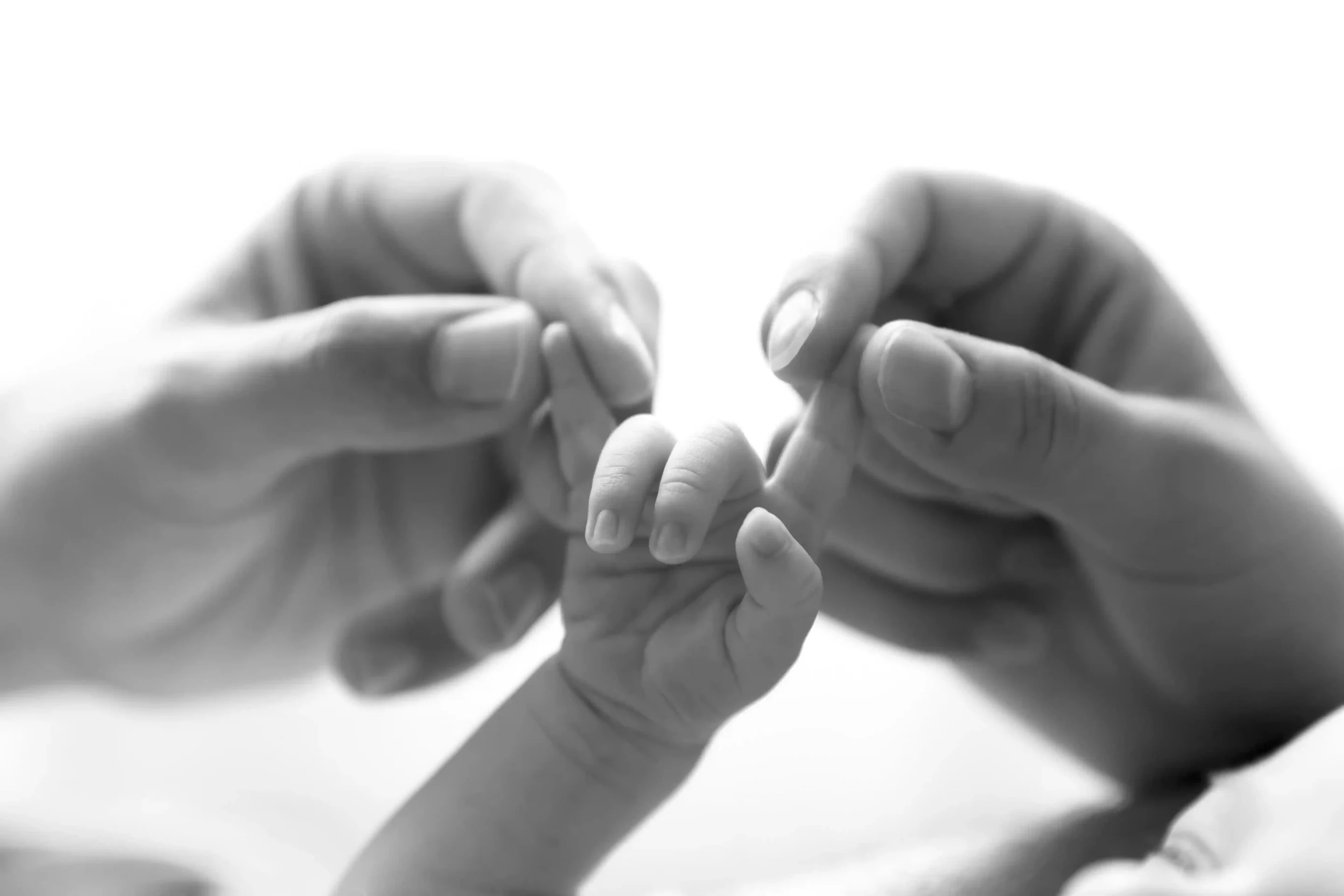 photo de naissance, gros plan sur les mains des parents tenant les doigts du bébé