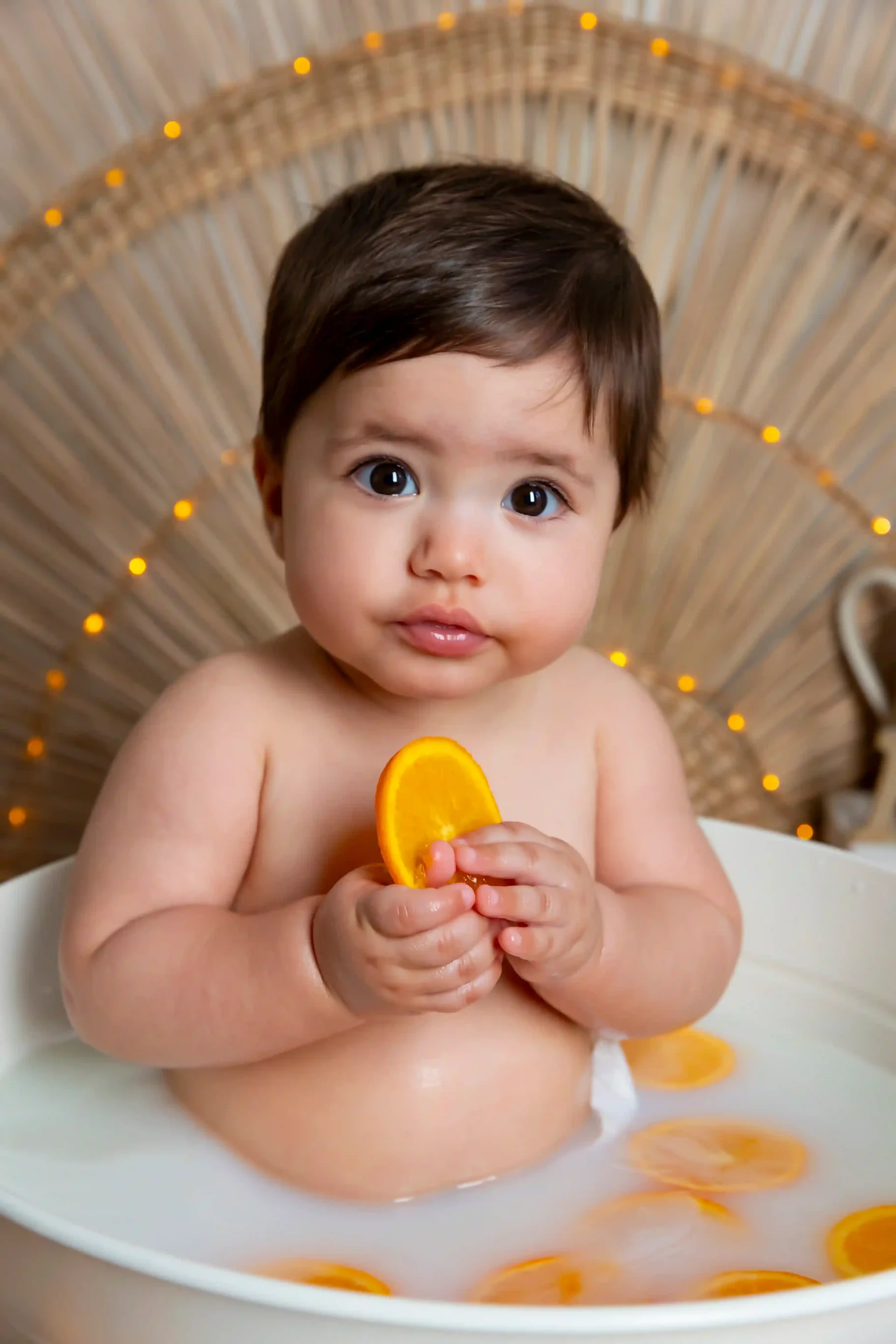 photo de bébé dans son bain de lait, entouré d'oranges