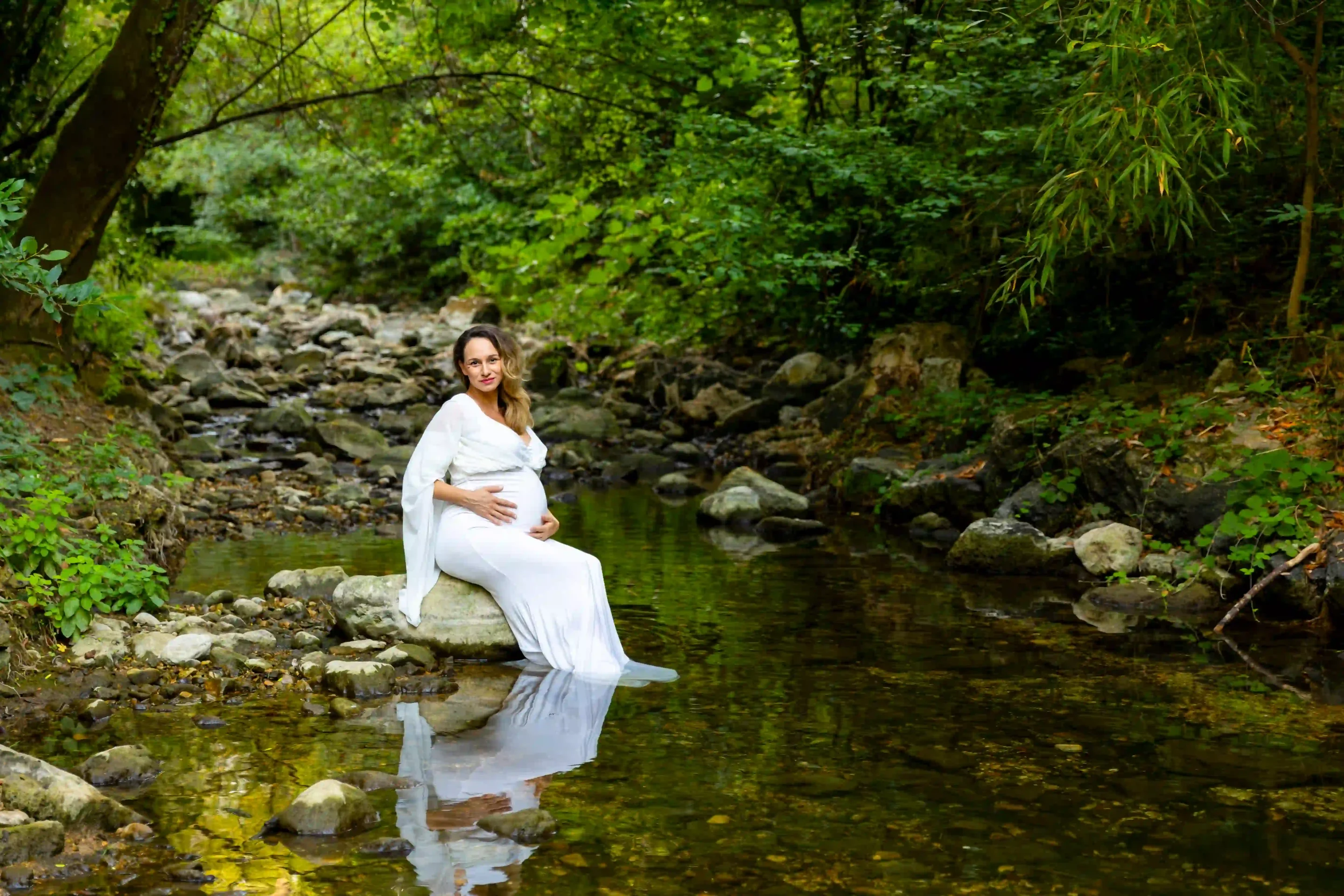 photo de grossesse, maman dans un rivière vêtue d'une robe blanche