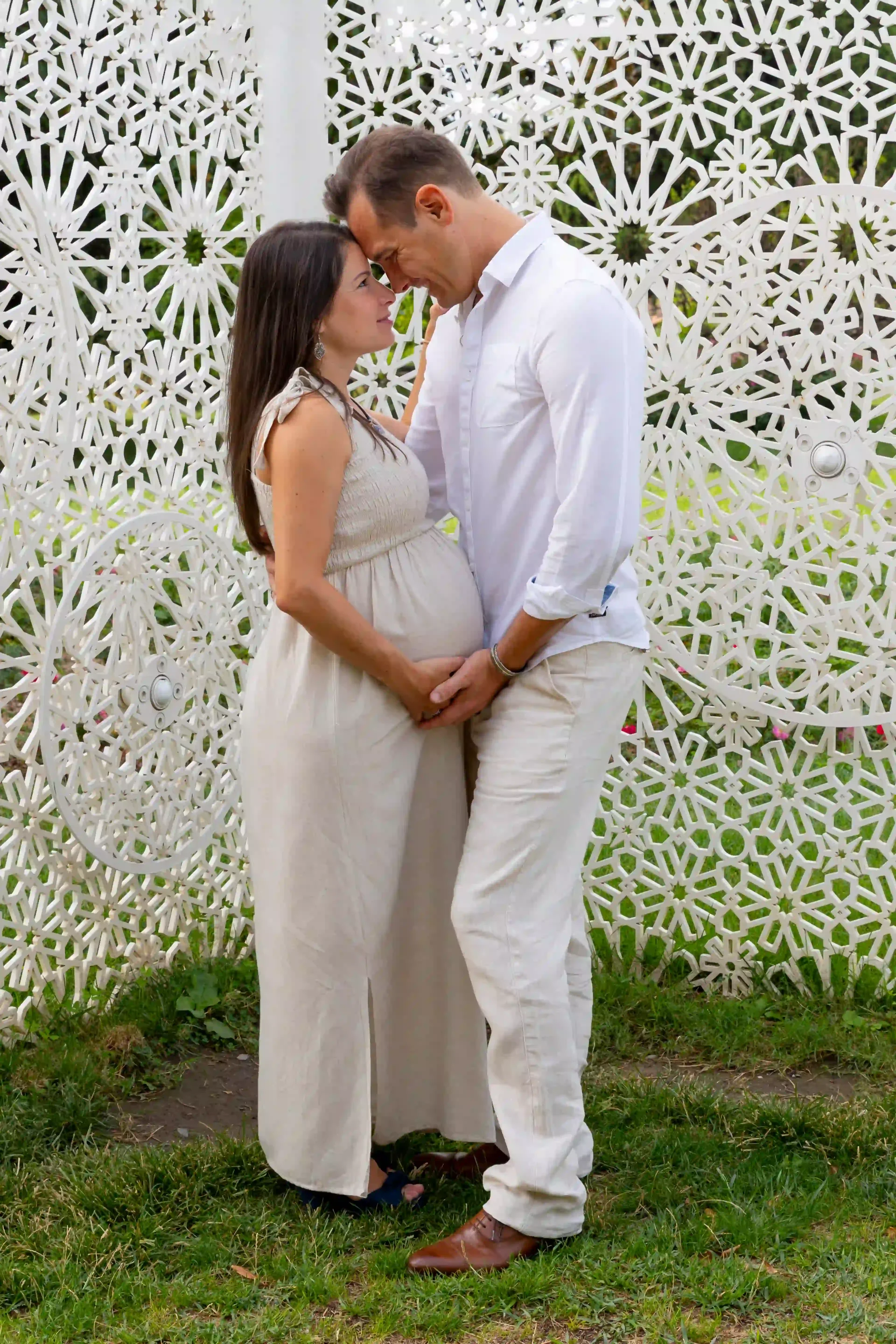 photo de grossesse, couple enlacé devant une structure blanche