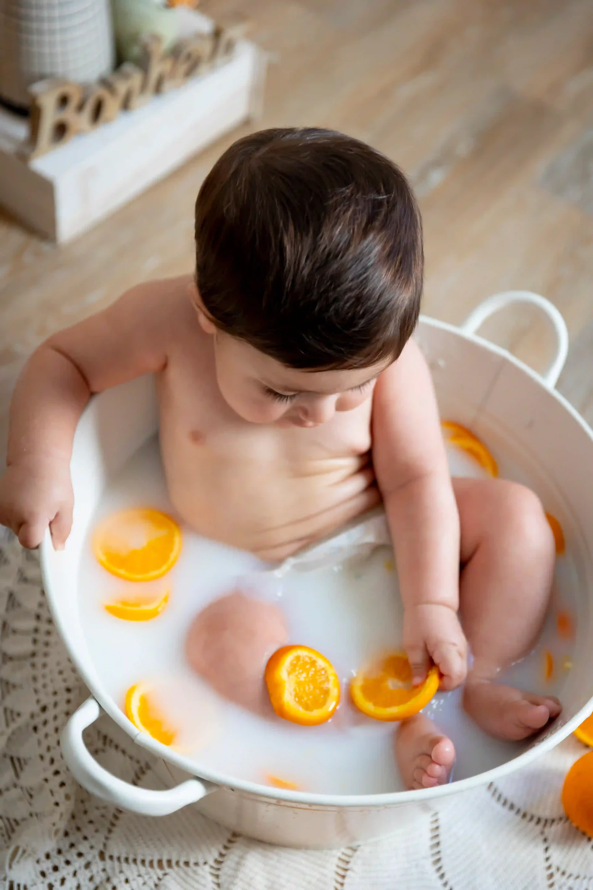 photo bain de lait, bébé entrain d'attraper une orange 