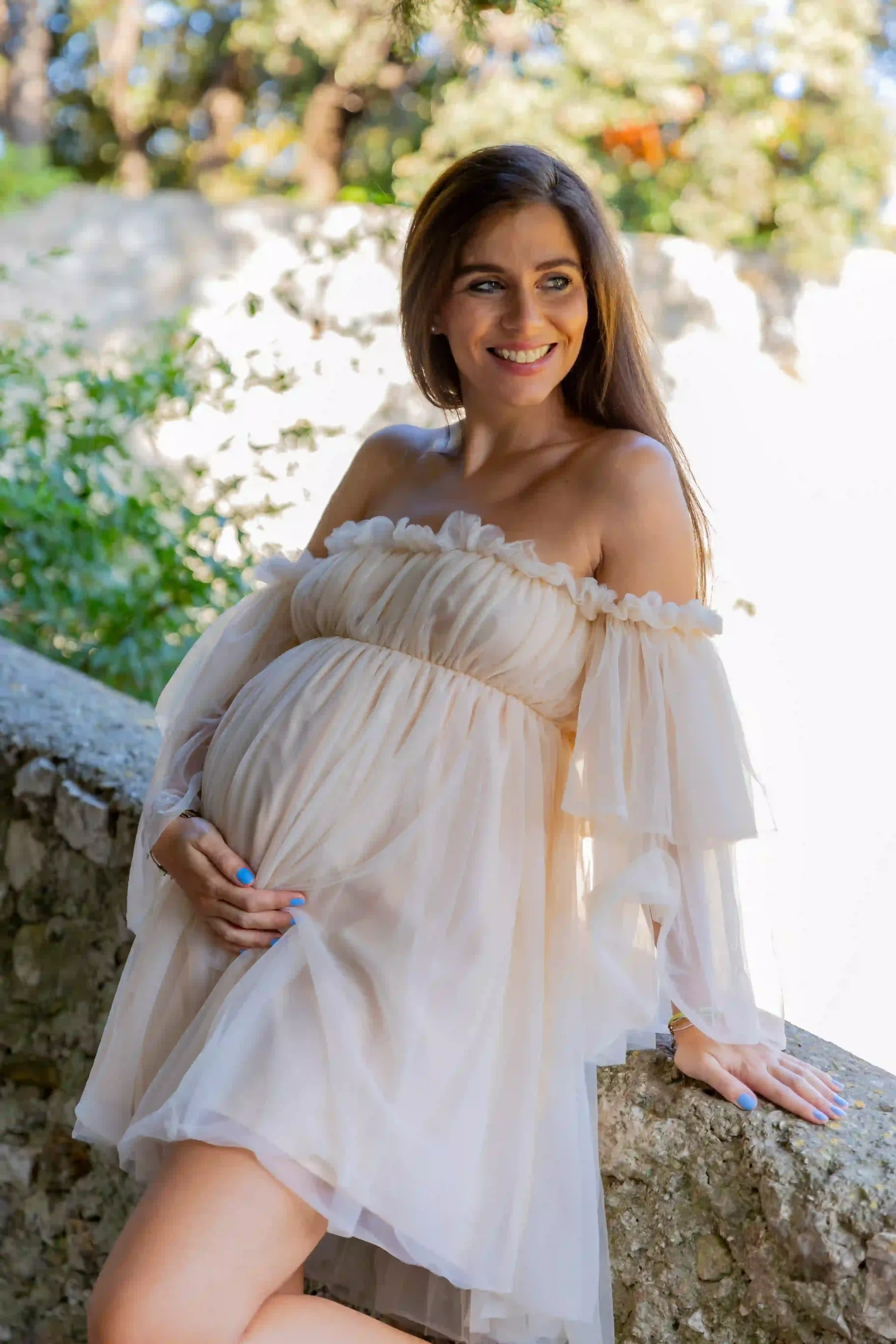 photo de grossesse, femme en robe de mousseline beige